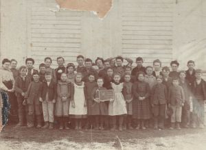Daisy Carson, my grandmother, is the teacher near the center with her hands on her head. I wish I knew more but there's no one left to ask. Look through your oldest photos with people who know the stories.  